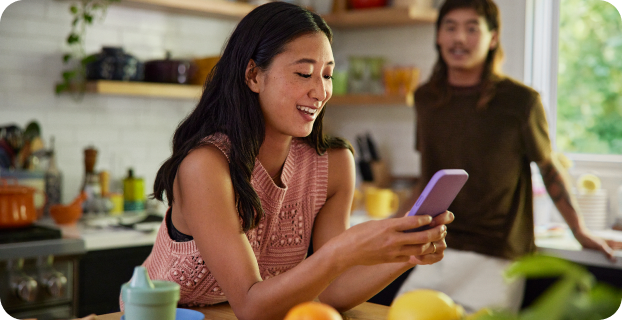 image of woman holding phone and man in background