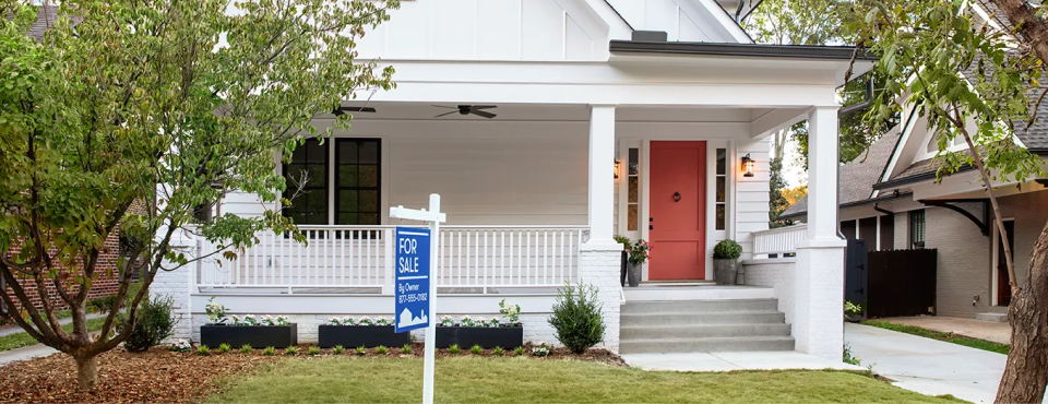 image of a white house with a sale sign in the yard