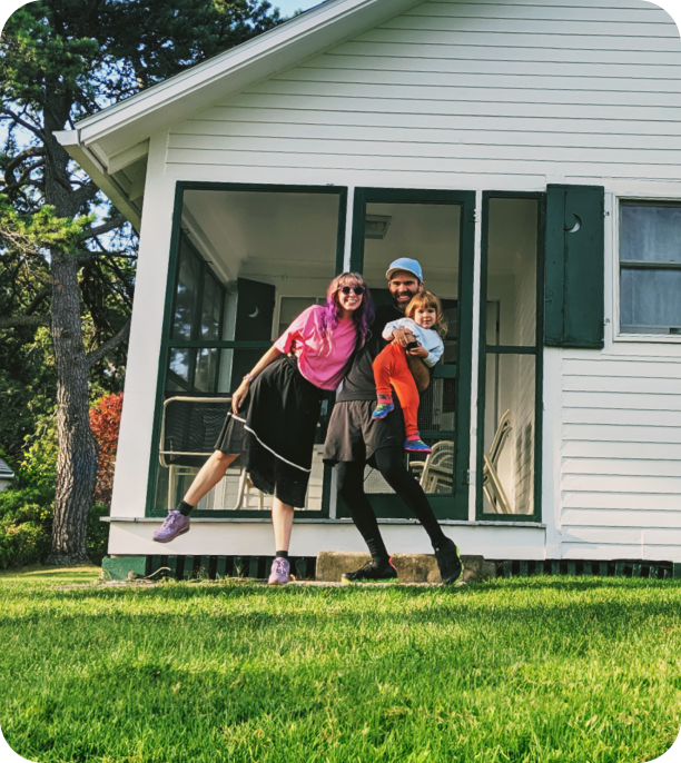 Image of young family standing in front of a house